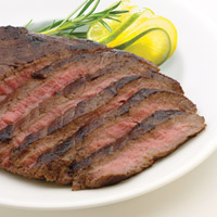 Grilled medium-cooked flank steak. Garnish of rosemary sprig